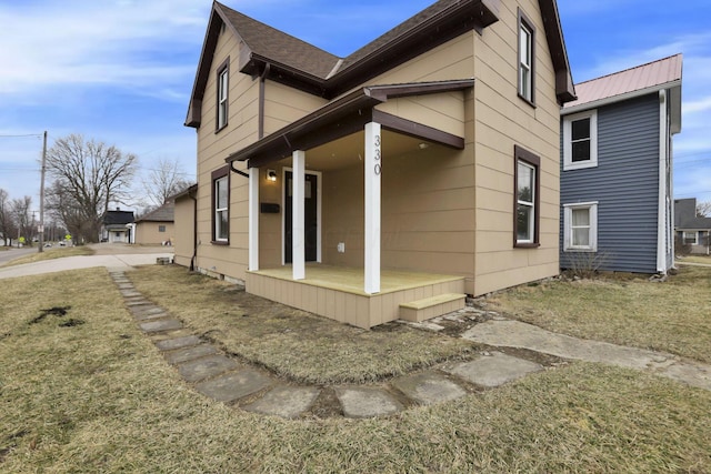 view of side of property featuring a porch and metal roof