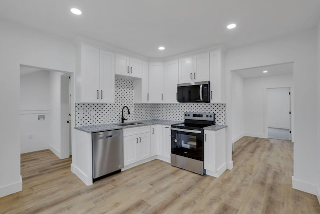 kitchen with light stone counters, white cabinets, stainless steel appliances, and a sink