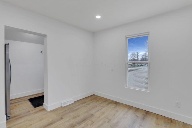 unfurnished room with light wood finished floors, visible vents, and baseboards