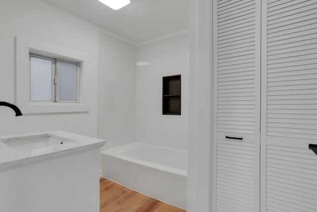 full bath featuring a closet, wood finished floors, vanity, and ornamental molding