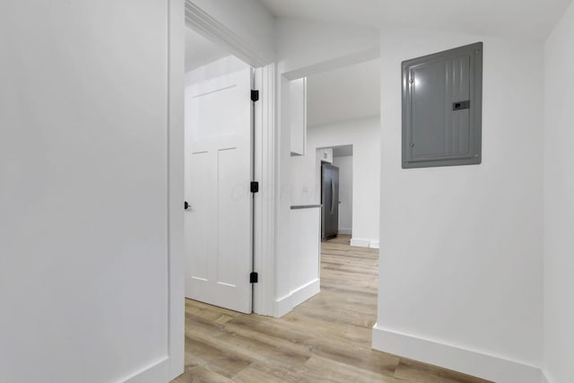 corridor featuring electric panel, baseboards, and light wood-style flooring