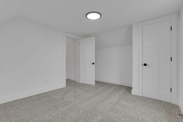 unfurnished bedroom with baseboards, carpet, and lofted ceiling