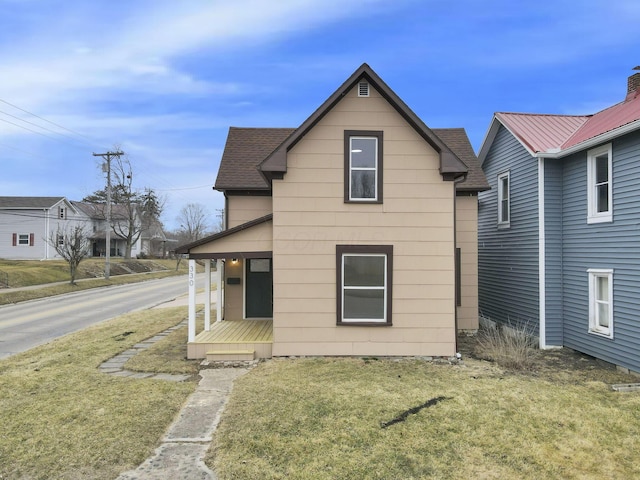 view of front of home with a front yard, a porch, and roof with shingles