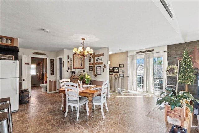 dining area featuring visible vents, an inviting chandelier, and stone finish flooring