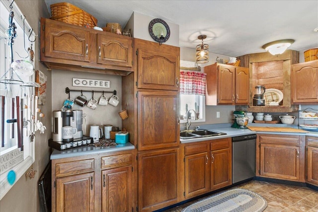 kitchen with a sink, brown cabinets, light countertops, and stainless steel dishwasher