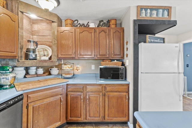 kitchen featuring stainless steel microwave, light countertops, dishwashing machine, brown cabinets, and freestanding refrigerator