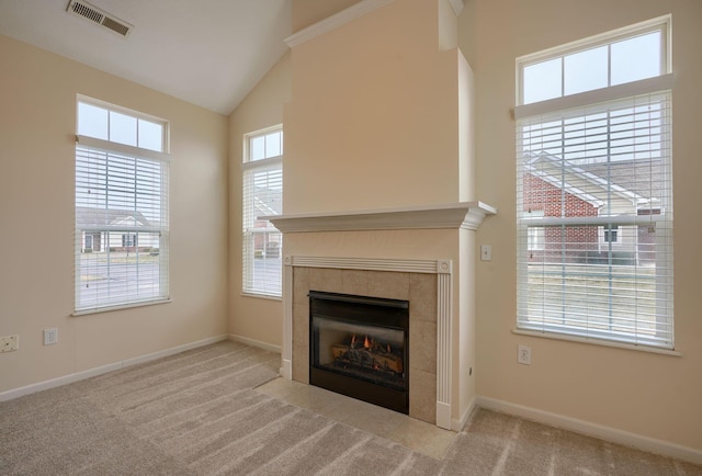 unfurnished living room featuring baseboards, visible vents, high vaulted ceiling, carpet floors, and a tile fireplace