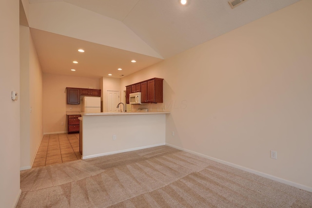 kitchen featuring light colored carpet, light countertops, lofted ceiling, recessed lighting, and white appliances