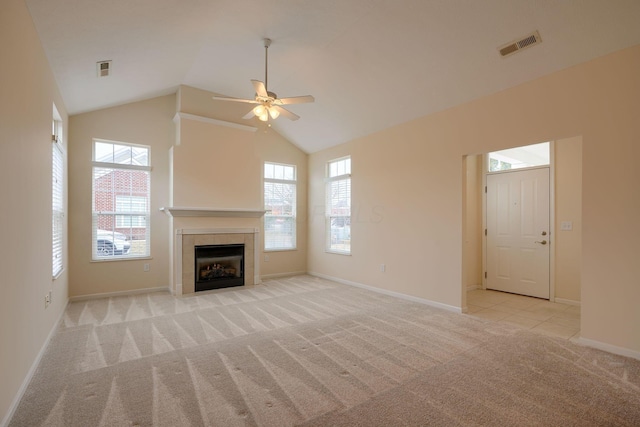 unfurnished living room featuring baseboards, visible vents, a tile fireplace, vaulted ceiling, and light colored carpet