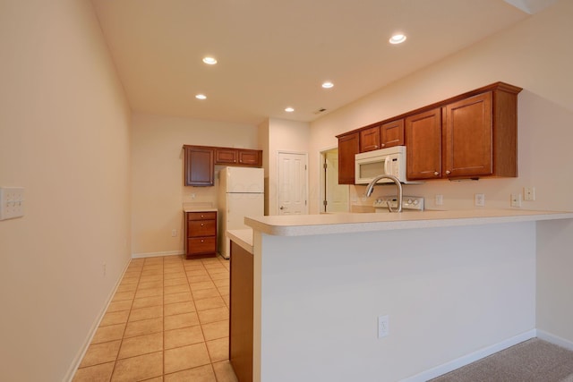 kitchen featuring brown cabinets, recessed lighting, white appliances, a peninsula, and light countertops