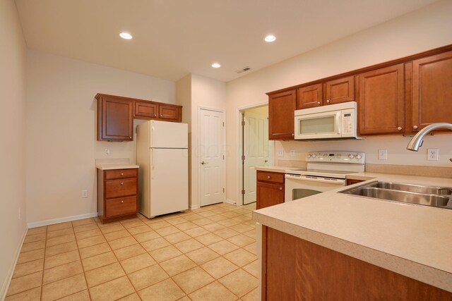 kitchen with visible vents, light countertops, brown cabinetry, white appliances, and a sink