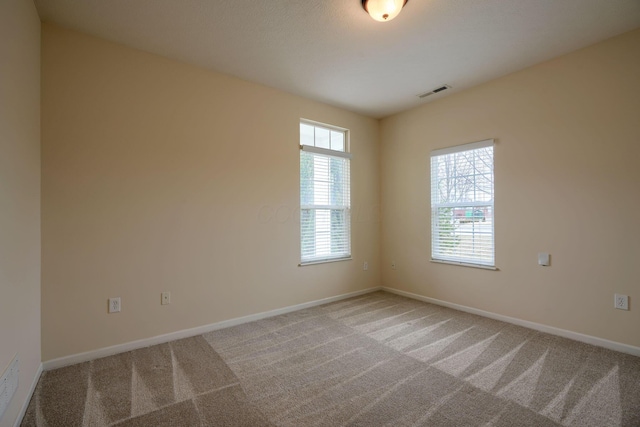 unfurnished room with baseboards, visible vents, and light carpet