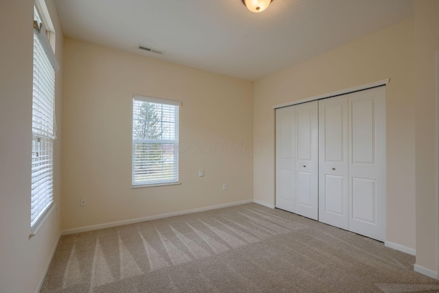 unfurnished bedroom with a closet, carpet flooring, baseboards, and visible vents