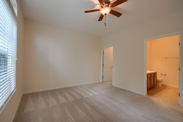 unfurnished bedroom featuring light carpet, ceiling fan, ensuite bathroom, and baseboards