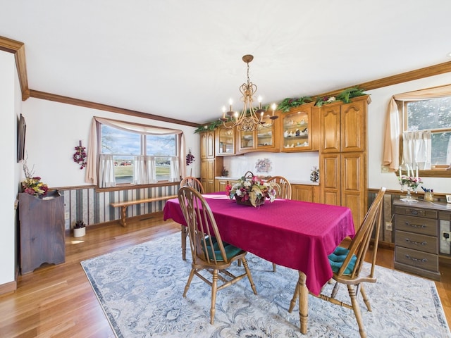 dining area featuring a notable chandelier, light wood-style flooring, and crown molding