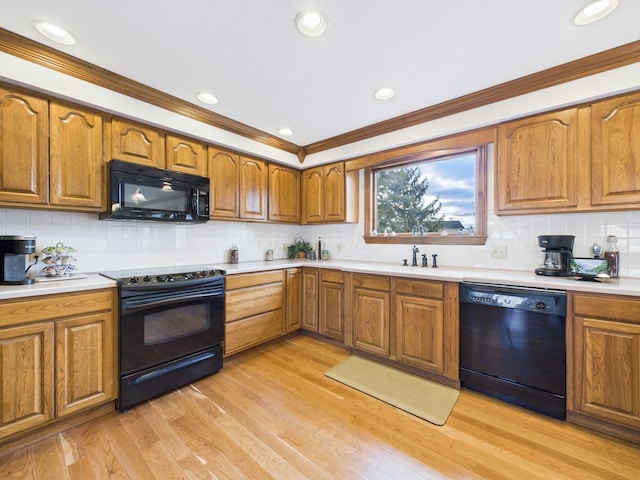 kitchen featuring brown cabinetry, light wood-style flooring, black appliances, and a sink