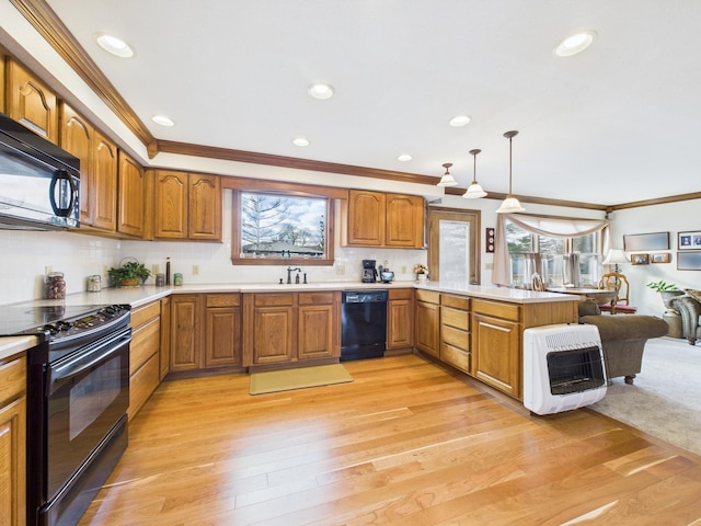 kitchen with crown molding, brown cabinets, a peninsula, heating unit, and black appliances