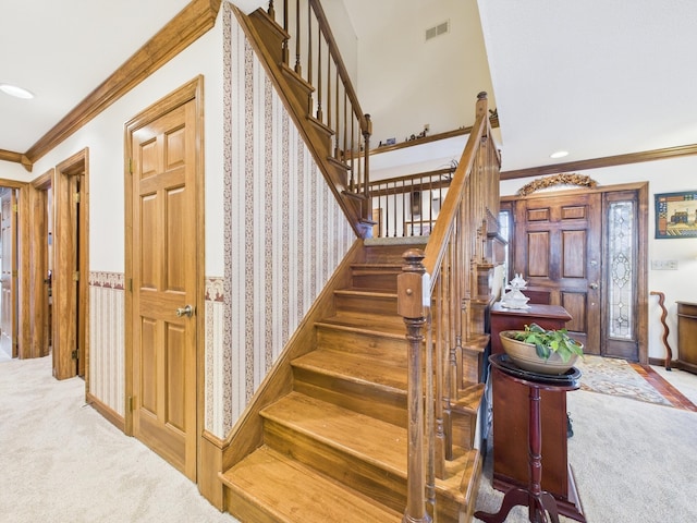 staircase featuring visible vents, ornamental molding, wallpapered walls, wainscoting, and carpet flooring