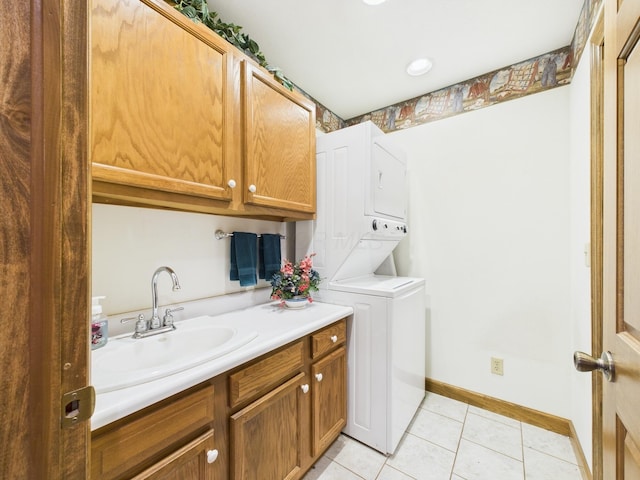 washroom featuring light tile patterned floors, baseboards, cabinet space, a sink, and stacked washer / drying machine