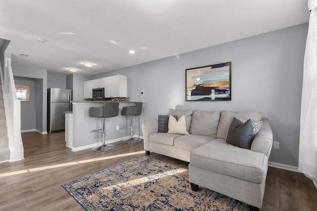 living area featuring recessed lighting, baseboards, wood finished floors, and stairs