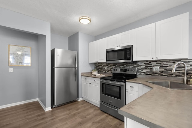 kitchen featuring a sink, white cabinets, tasteful backsplash, and stainless steel appliances