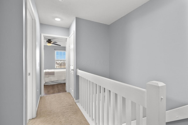 corridor featuring an upstairs landing and carpet flooring