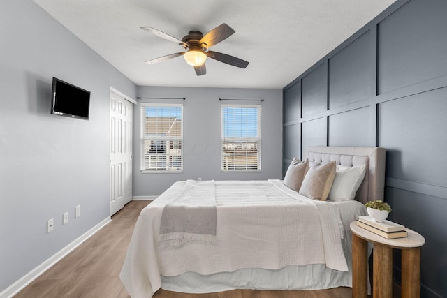 bedroom featuring light wood-style flooring, a ceiling fan, and baseboards