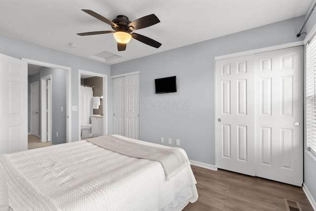 bedroom with visible vents, baseboards, multiple closets, and wood finished floors