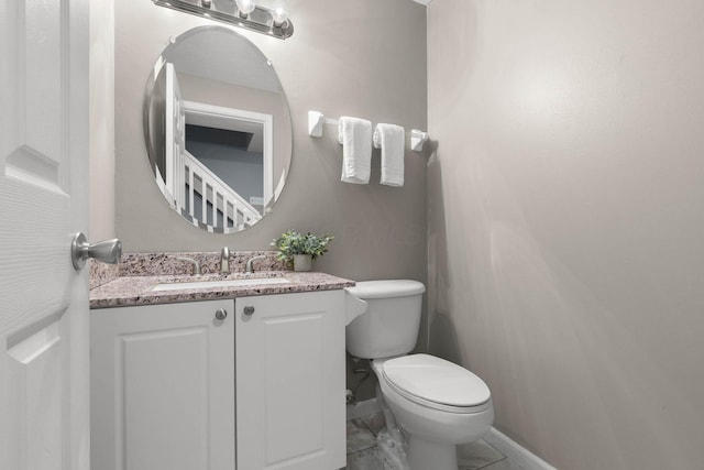 half bathroom with toilet, vanity, and baseboards