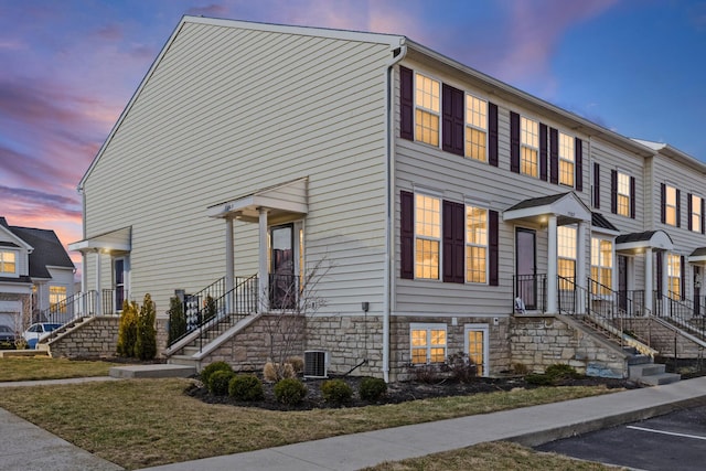 view of property featuring stone siding and central air condition unit