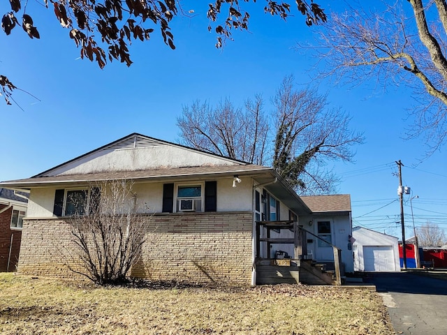 view of front facade featuring brick siding, stucco siding, driveway, and an outdoor structure