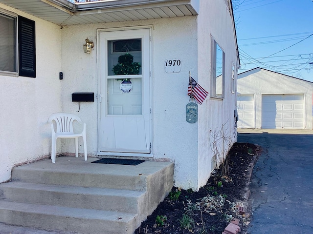 doorway to property with stucco siding and a detached garage