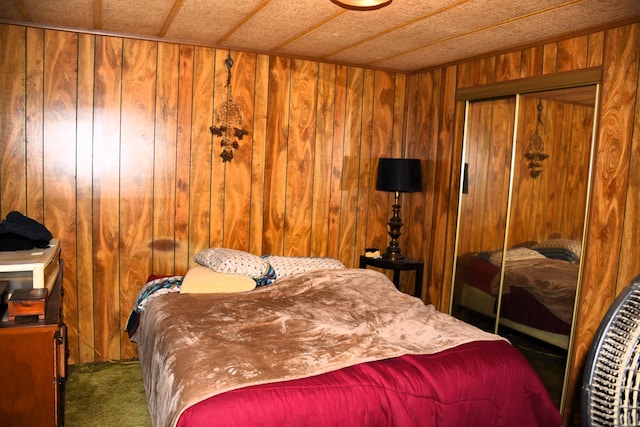 carpeted bedroom with a closet and wood walls