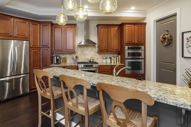 kitchen featuring wall chimney range hood, decorative backsplash, a kitchen breakfast bar, dark wood-style floors, and stainless steel appliances