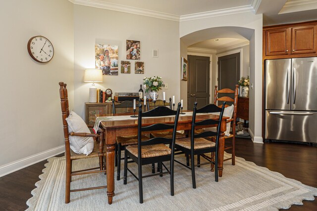 dining space featuring wood finished floors, baseboards, arched walkways, and ornamental molding