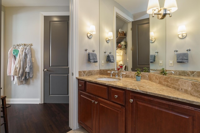 bathroom with vanity, wood finished floors, baseboards, and a chandelier