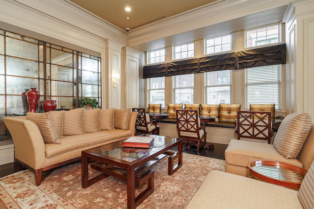 living area featuring a wealth of natural light, crown molding, and light wood-style floors