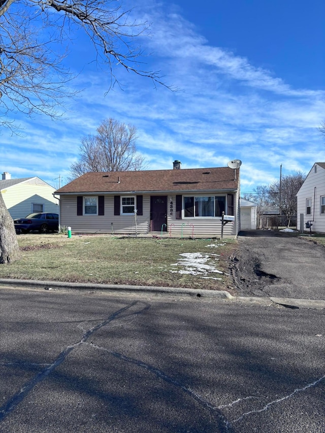 view of front facade featuring a front lawn, an outdoor structure, and aphalt driveway