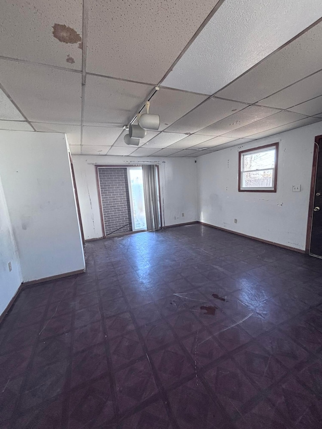 empty room with tile patterned floors, baseboards, and a paneled ceiling