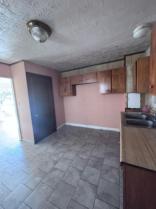 kitchen featuring brown cabinetry, baseboards, and a sink