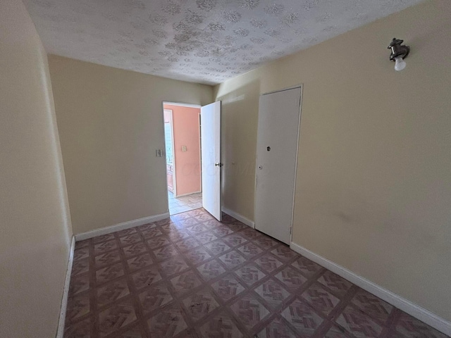 unfurnished room with tile patterned floors, baseboards, and a textured ceiling