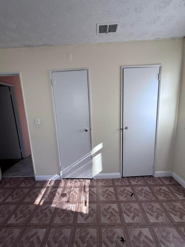 unfurnished bedroom with visible vents, baseboards, and a textured ceiling