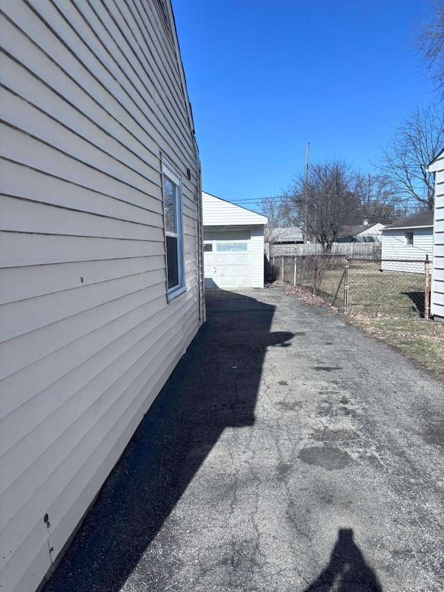 view of side of home featuring a garage, an outbuilding, driveway, and fence