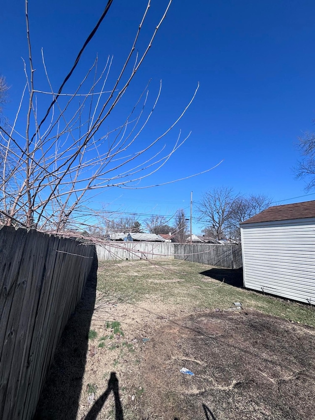 view of yard with a storage unit, an outdoor structure, and a fenced backyard