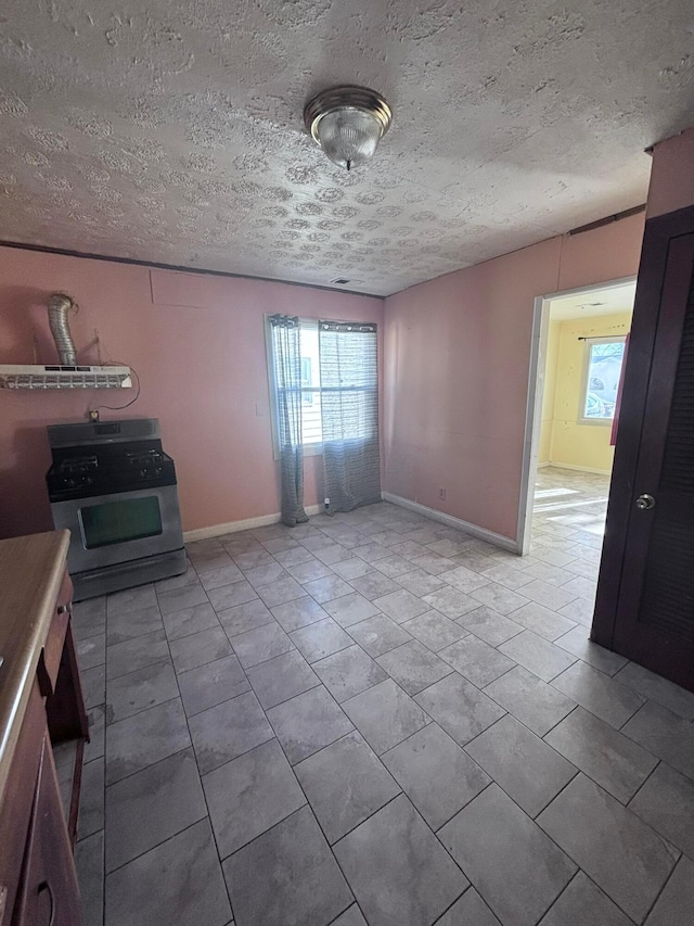 interior space featuring baseboards, a textured ceiling, and tile patterned flooring