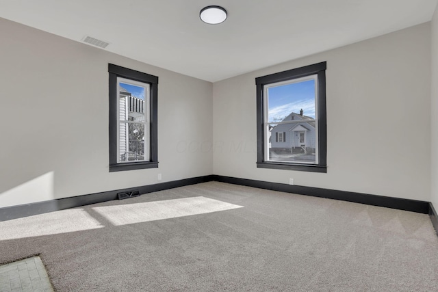 empty room featuring visible vents, light colored carpet, and baseboards