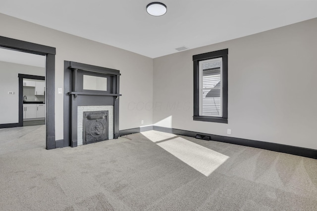 interior space with visible vents, a fireplace with flush hearth, carpet, and baseboards