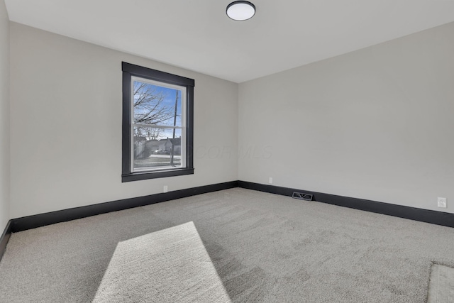 unfurnished room with carpet, visible vents, and baseboards