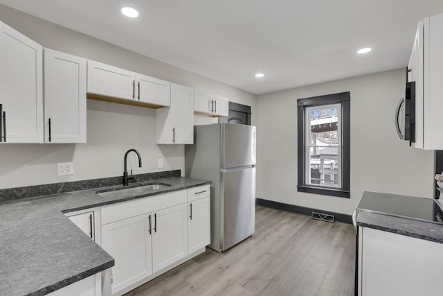 kitchen featuring a sink, stainless steel appliances, visible vents, and white cabinetry