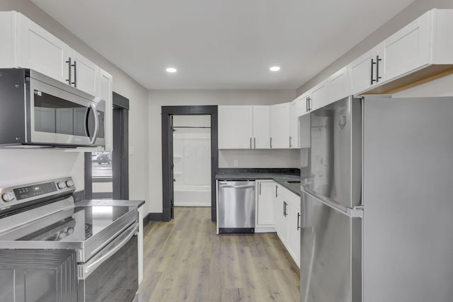 kitchen with light wood-style floors, appliances with stainless steel finishes, and white cabinetry